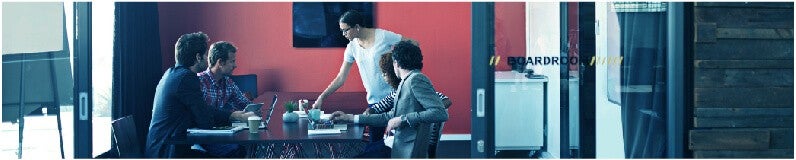 Woman wearing glasses in a meeting about customer feedback with four people in a boardroom.