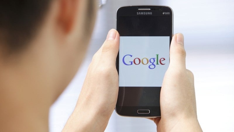 Man holding a cell phone with Google on screen.
