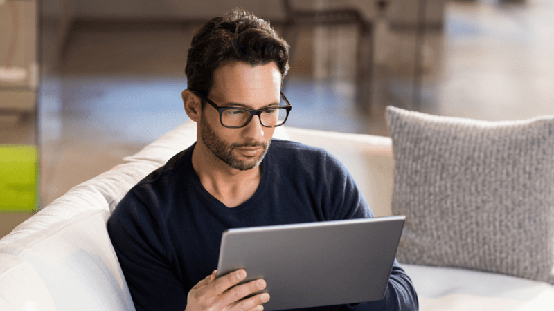Man sitting on a couch using a tablet.