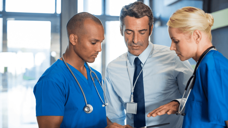 Three medical personnel discussing a patient's chart.