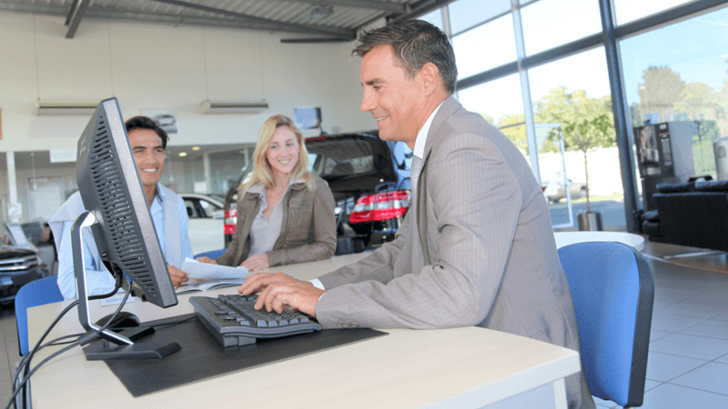 Young couple purchasing a car from an auto dealership.