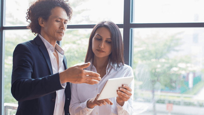 Two people discussing a project while looking at a document.