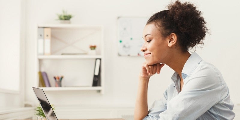 Woman looking at her laptop screen smiling.