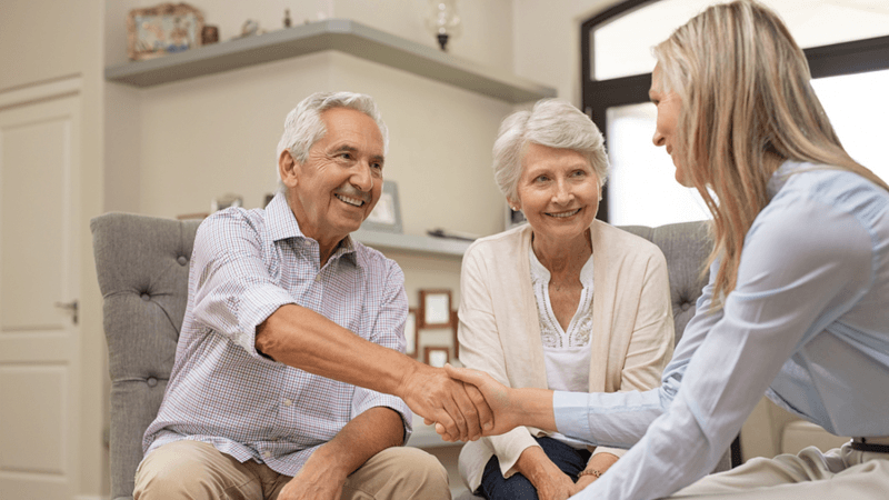 Happy couple shaking hands with a business owner.