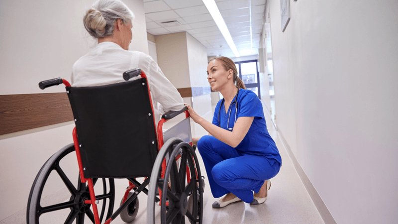 Medical worker assisting a woman in a wheelchair.