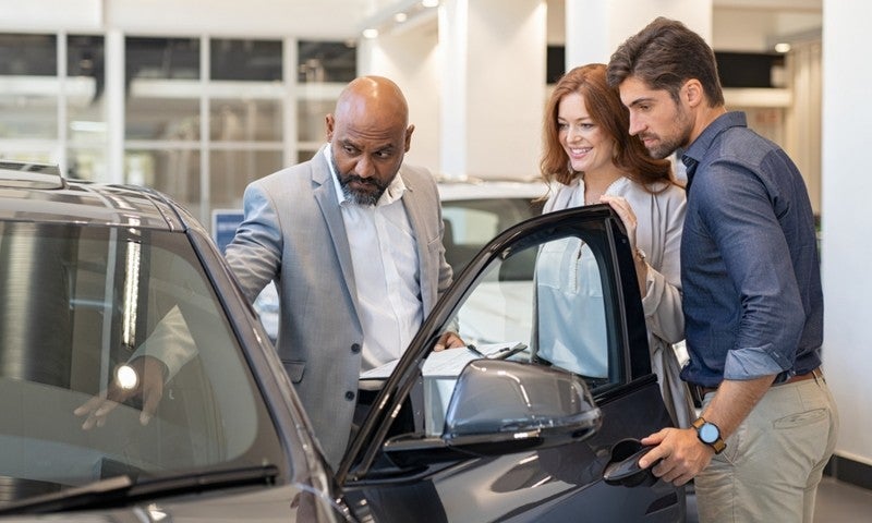 Couple looking at a new car with a salesman.