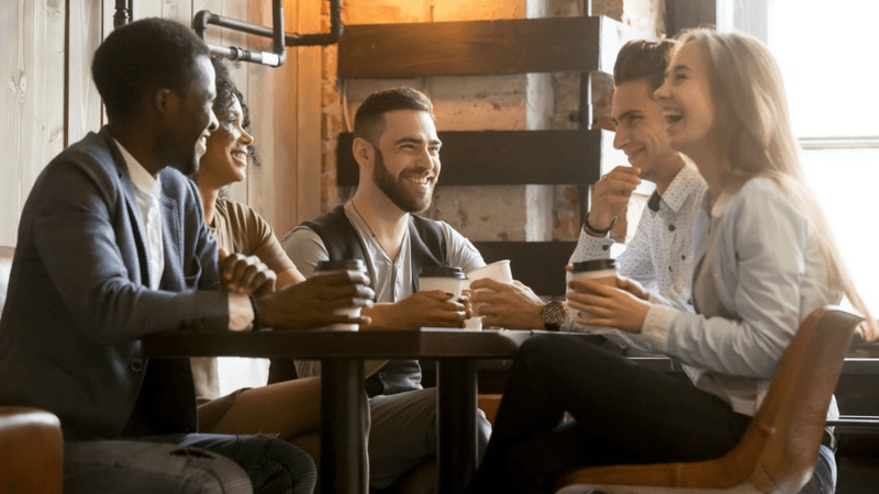 Group of men and women sitting around a table talking and smiling.