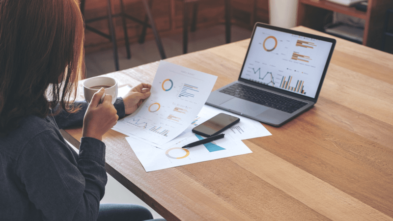 Person looking at charts and graphs on a document.