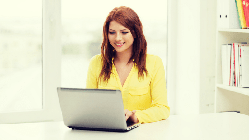 Smiling woman typing on a laptop.