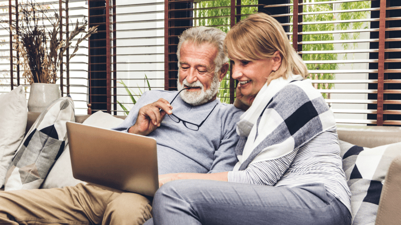 Smiling couple looking at a laptop together.