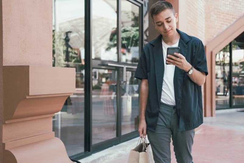 Man holding a shopping bag and looking at his phone.