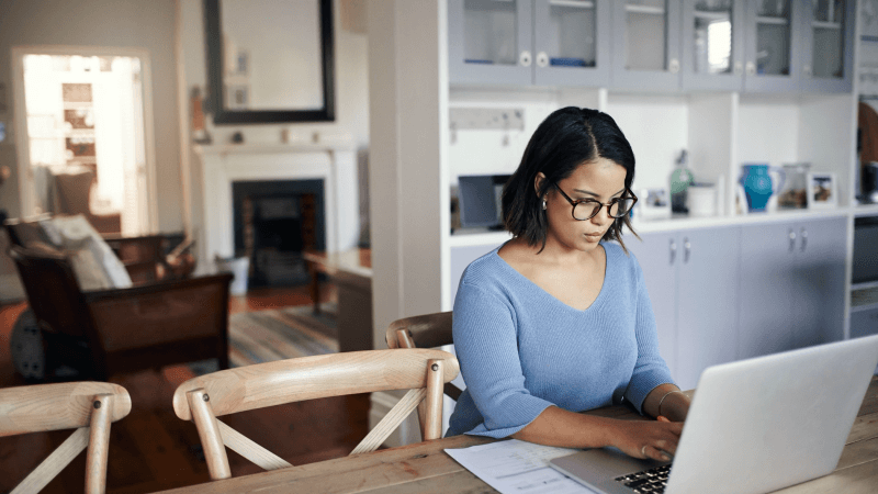 Woman wearing glasses while typing on a laptop computer.