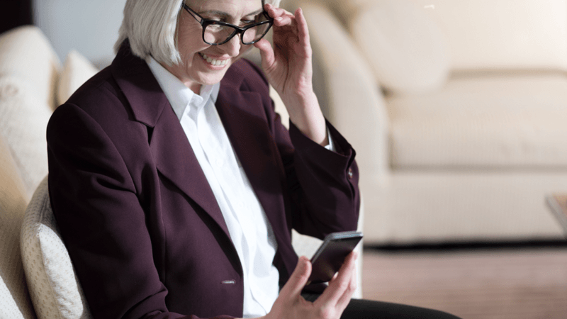 Woman wearing glasses and looking at her phone.