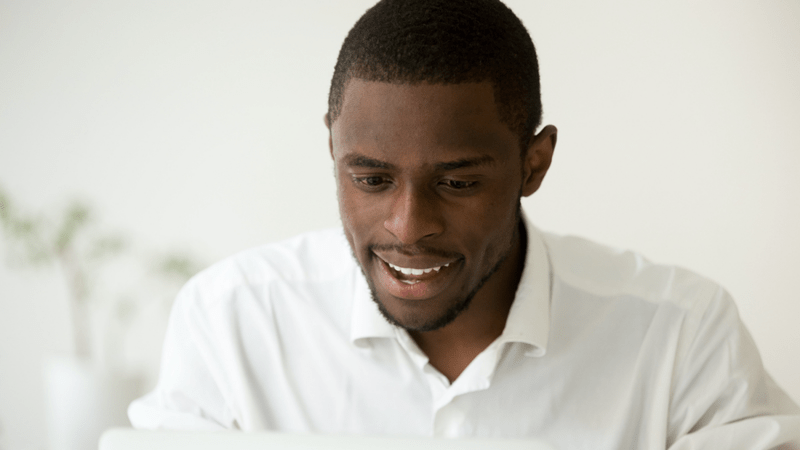 Smiling man while looking at his laptop.