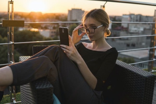 Woman sitting on a balcony looking at her phone. Woman sitting on a balcony looking at her phone.