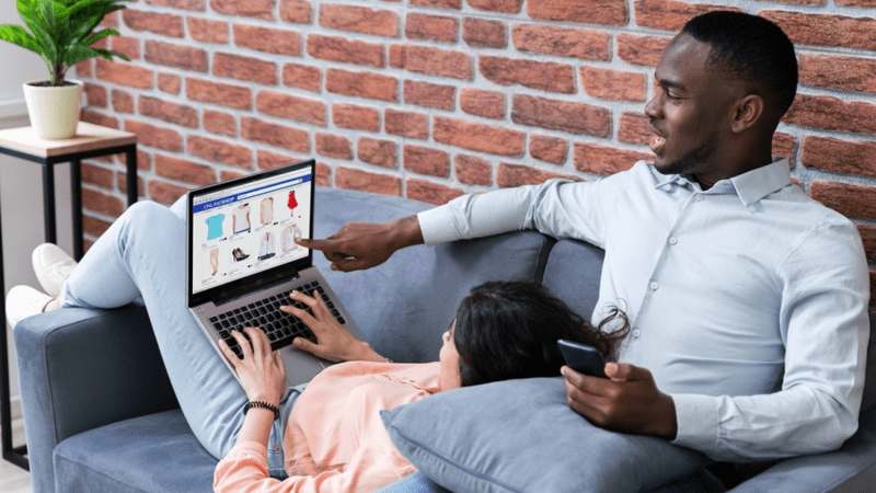Couple sitting on a couch looking at a website.