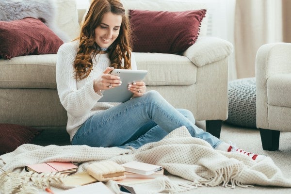 Woman sitting on the floor looking at her tablet. Woman sitting on the floor looking at her tablet.