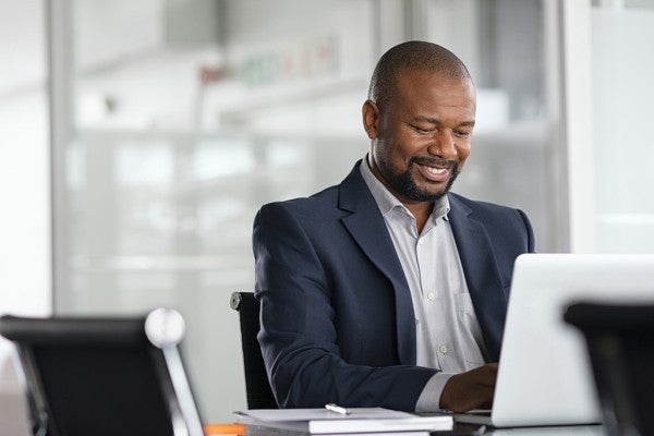 Smiling man typing on a laptop computer. Smiling man typing on a laptop computer.
