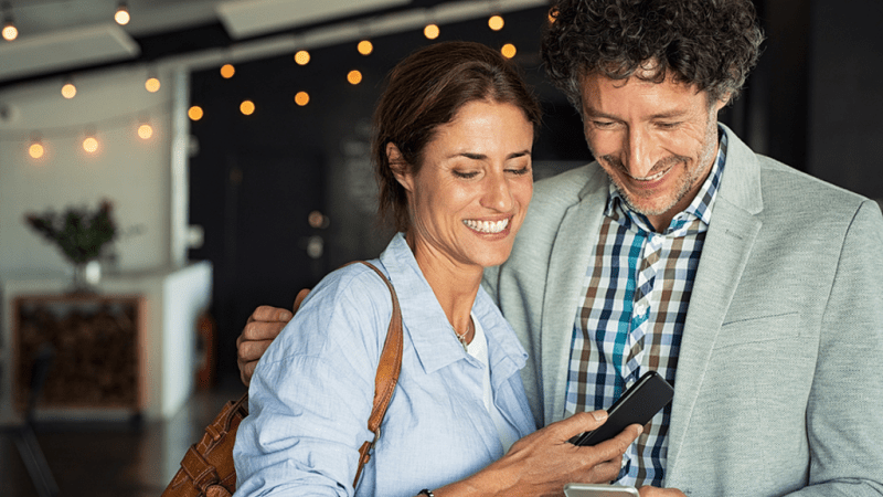 Happy couple looking at a phone together.