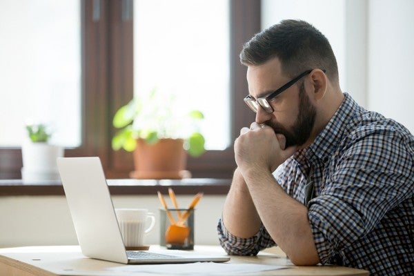 Man staring intently at his computer screen. Man staring intently at his computer screen.