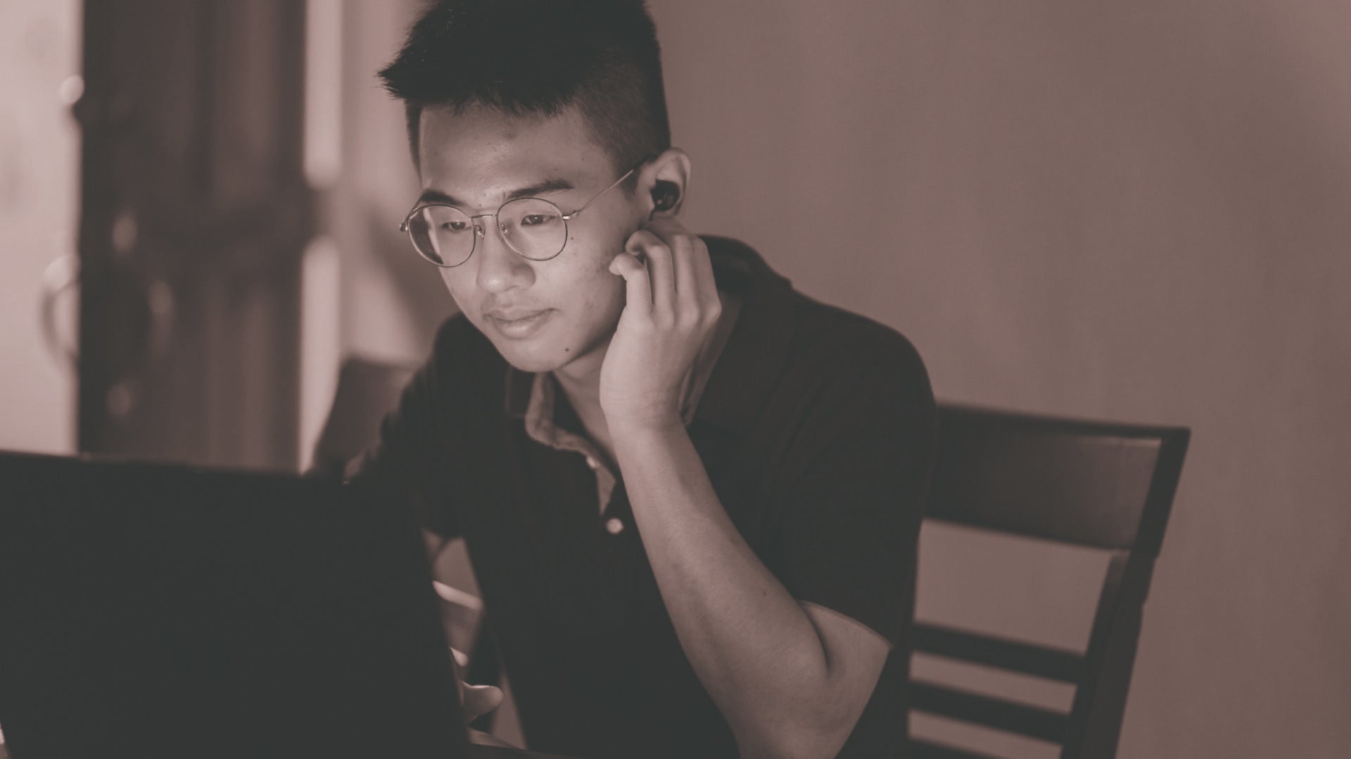 Male Student on Laptop with hand on chin